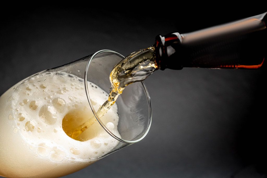 Beer pouring into a glass with foam on a dark background