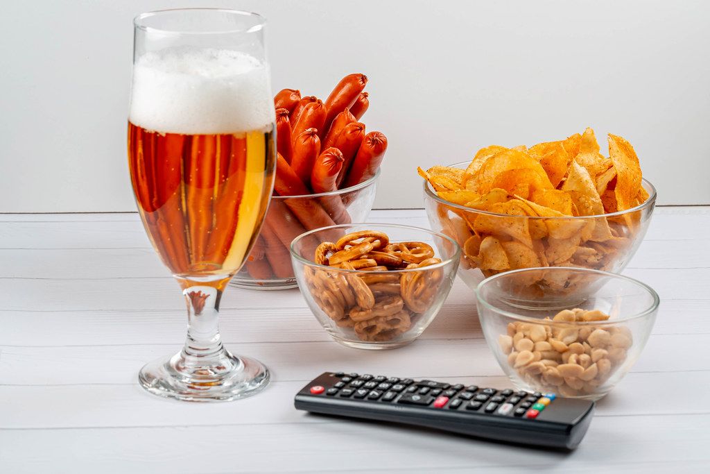 Beer, sausage, chips and peanuts with TV remote
