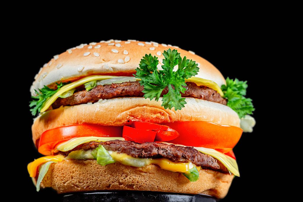 Big burger with vegetables and cutlets on a black background
