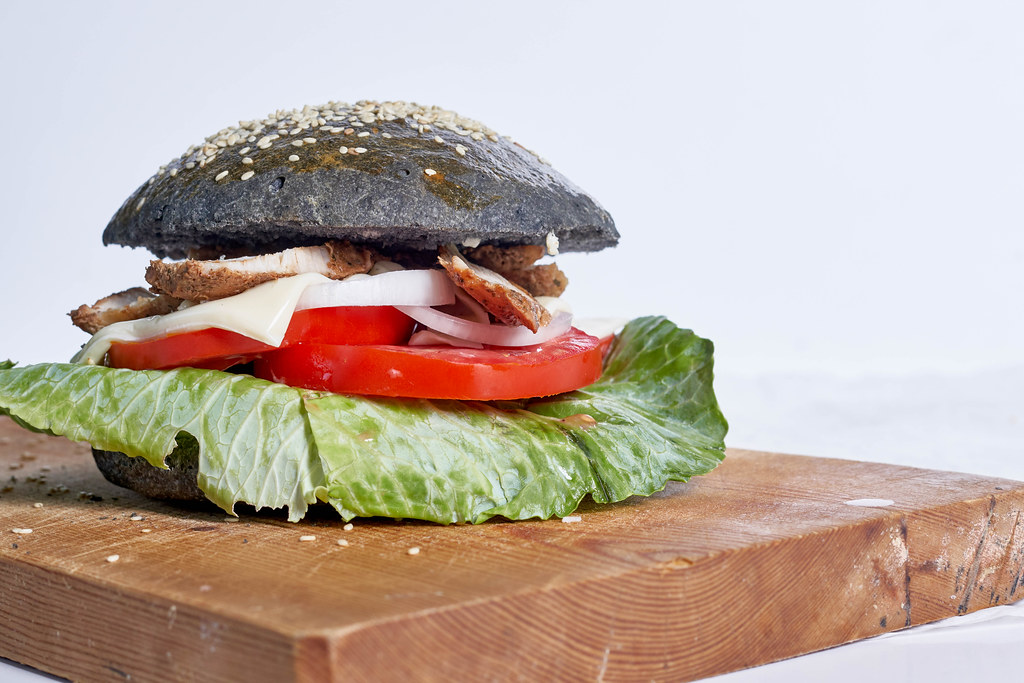 Black hamburger with juicy meat, tomato, onion and cheese