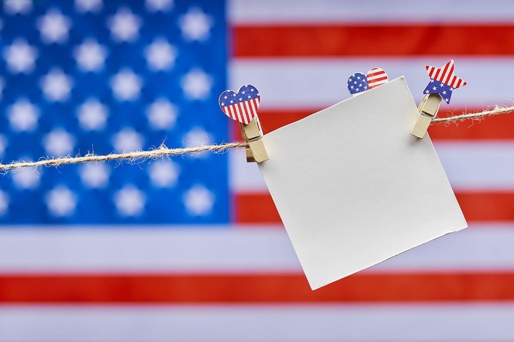 Blank card hanged on the rope with decorative clothespins colored in USA national symbols