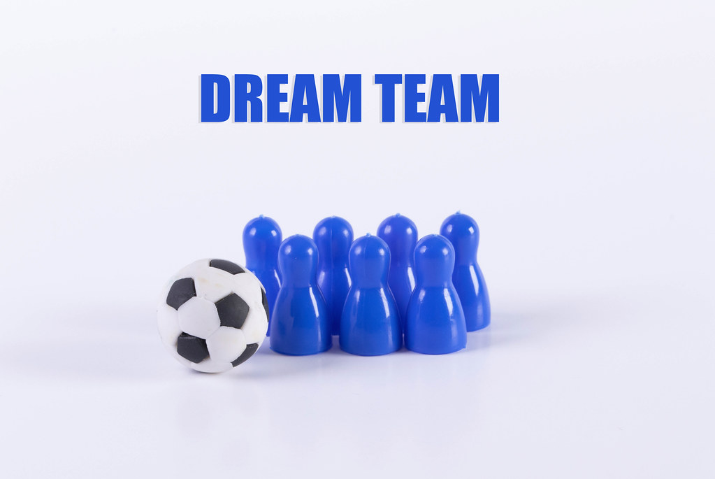 Blue board game pawn figures with soccer ball and Dream team text
