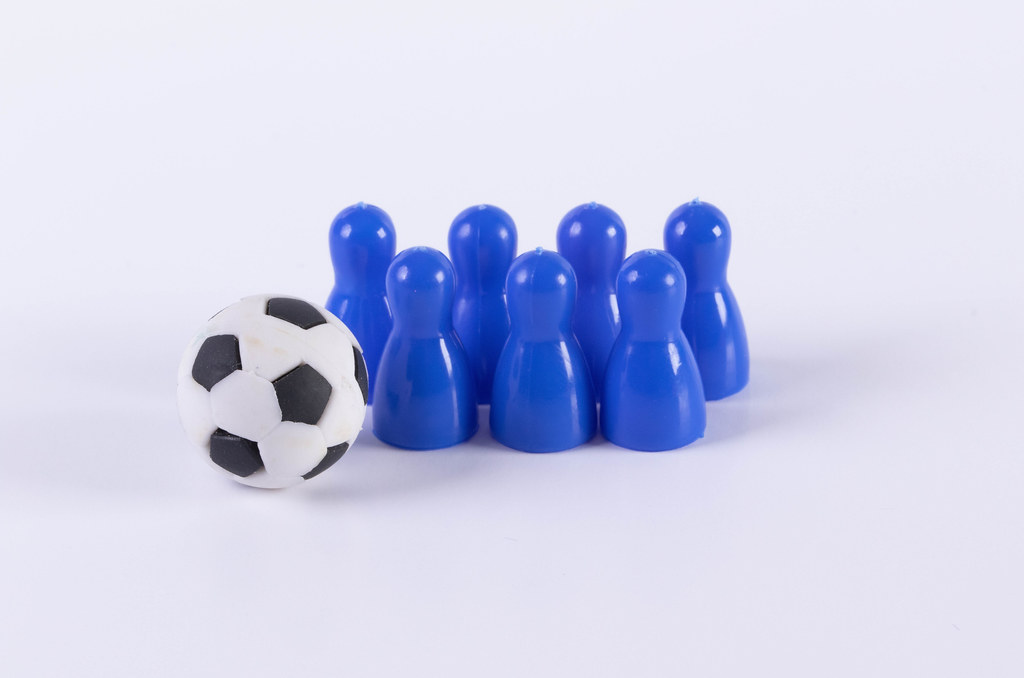 Blue board game pawn figures with soccer ball
