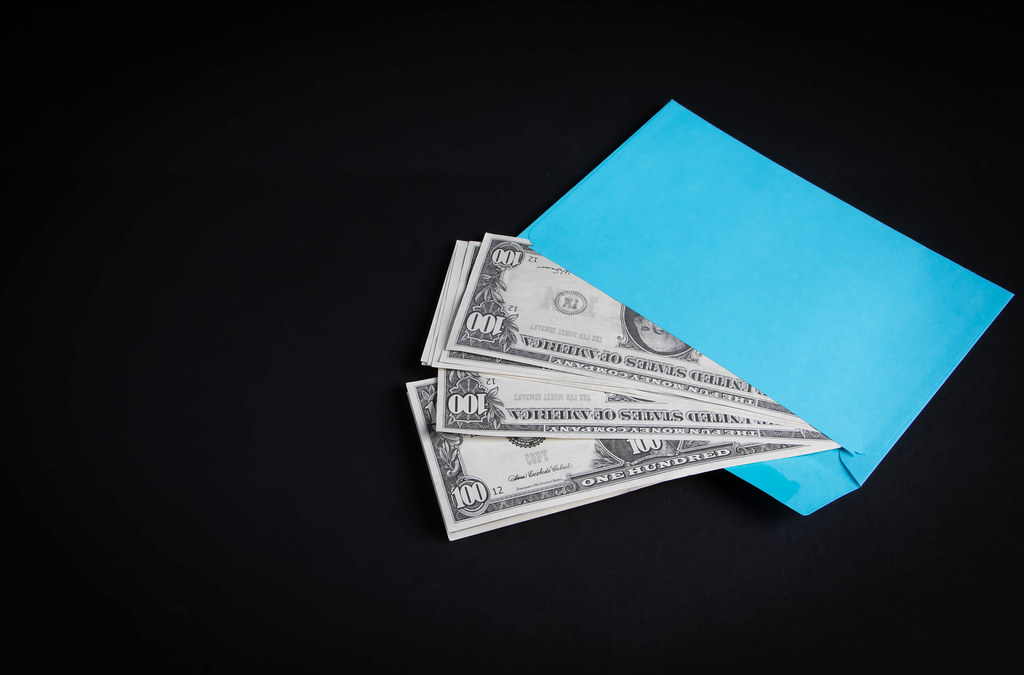 Blue envelope with money on black background