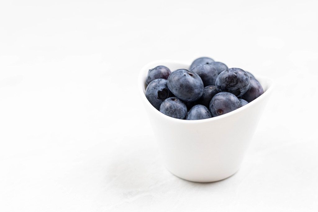 Blueberries in the bowl with copy space above white background