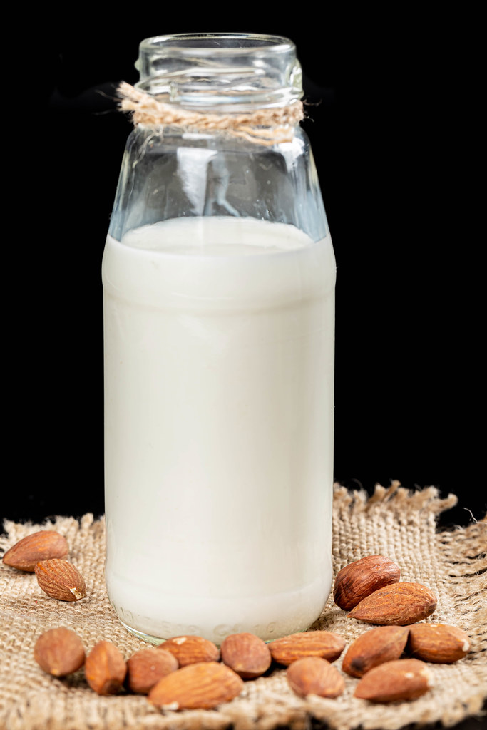 Bottle of almonds milk with almonds on burlap