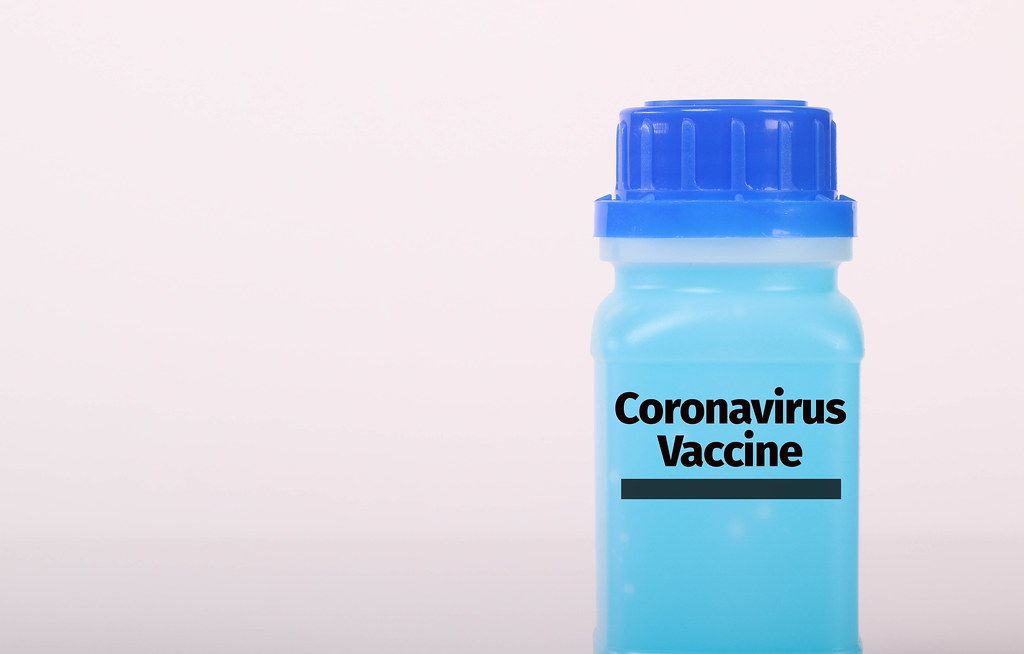 Bottle with blue fluid and Coronavirus Vaccine text