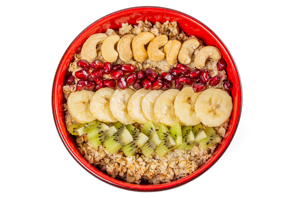 Bowl of oatmeal with fresh fruit and cashew nuts, top view