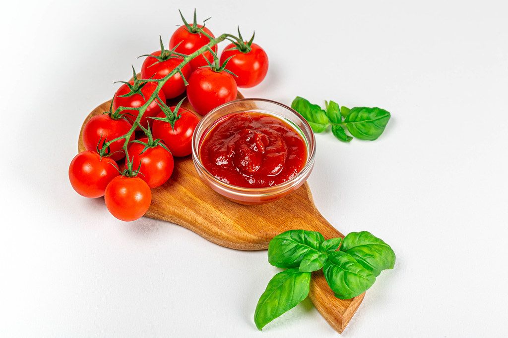 Bowl with ketchup, fresh tomatoes and basil leaves