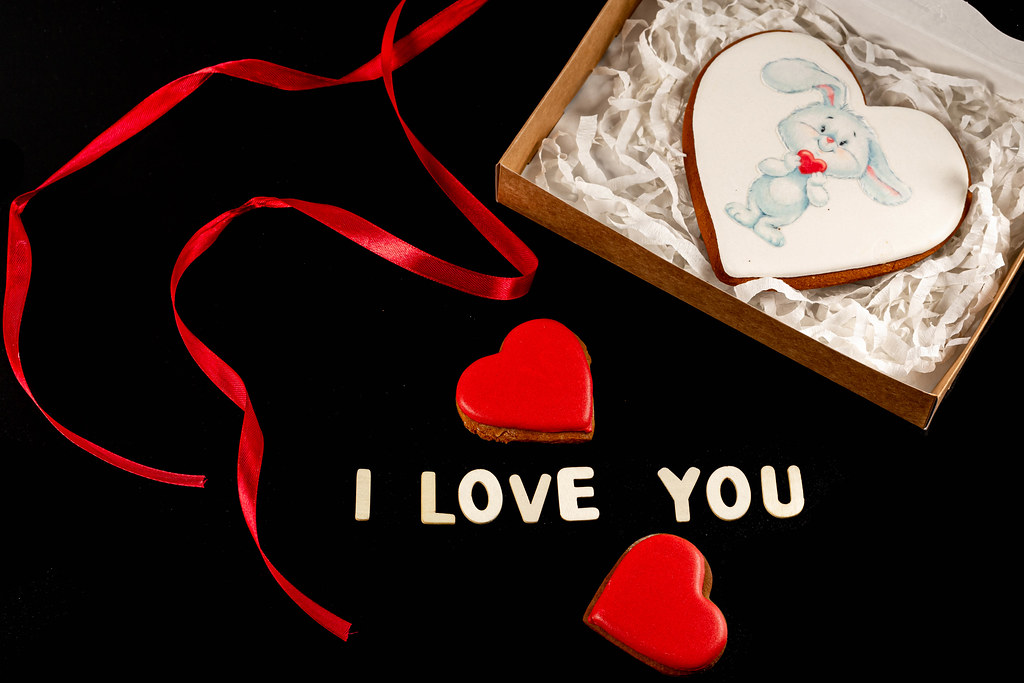 Box with gingerbread for valentine's day on a dark background with a red ribbon and the words - I love you