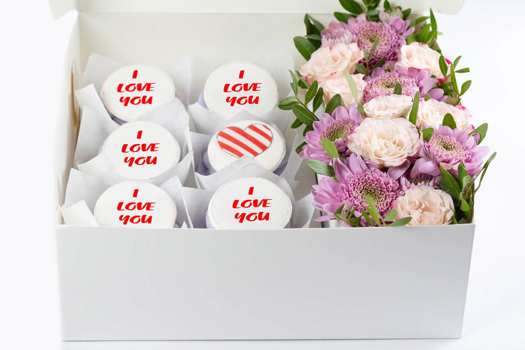 Box with muffins and flowers in pink and purple colors