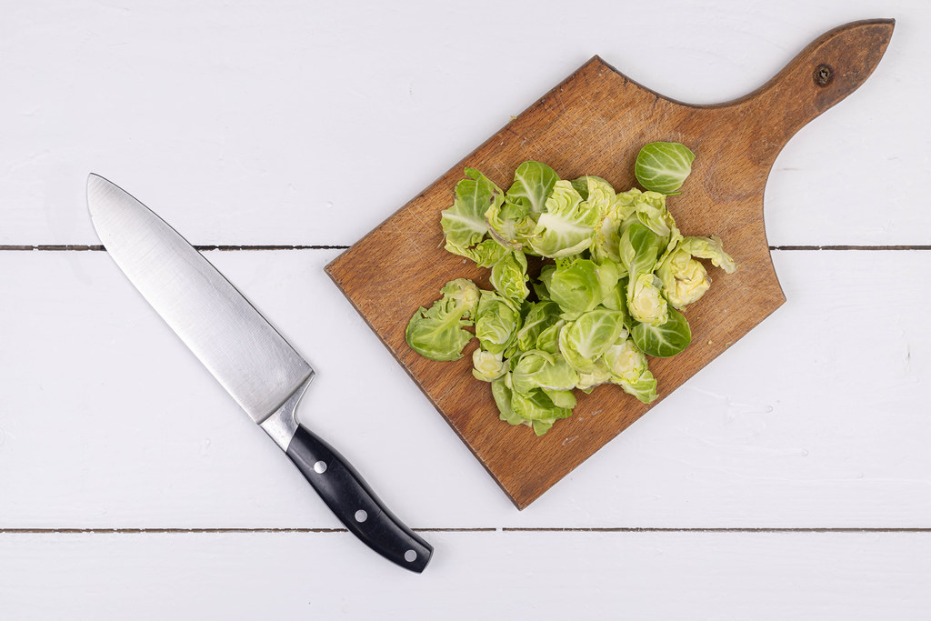 Brussel Sprouts slices on the wooden board with knife