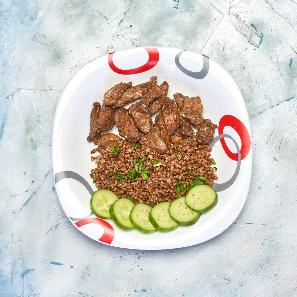 Buckwheat, chicken fillet and cucumber slices on the plate