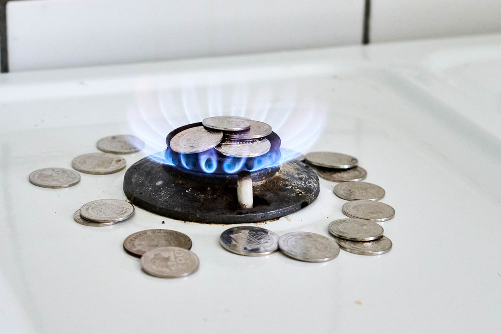 Burning natural gas and pile of coins on gas hob