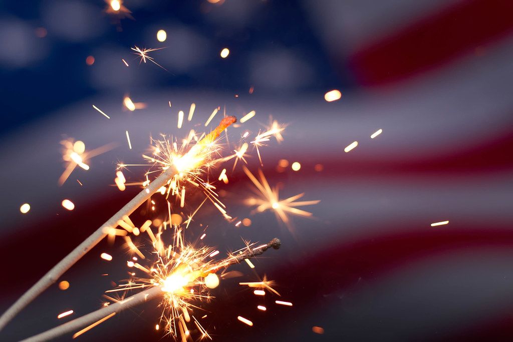 Burning sparklers against USA flag. Celebrating US national holiday with sparklers