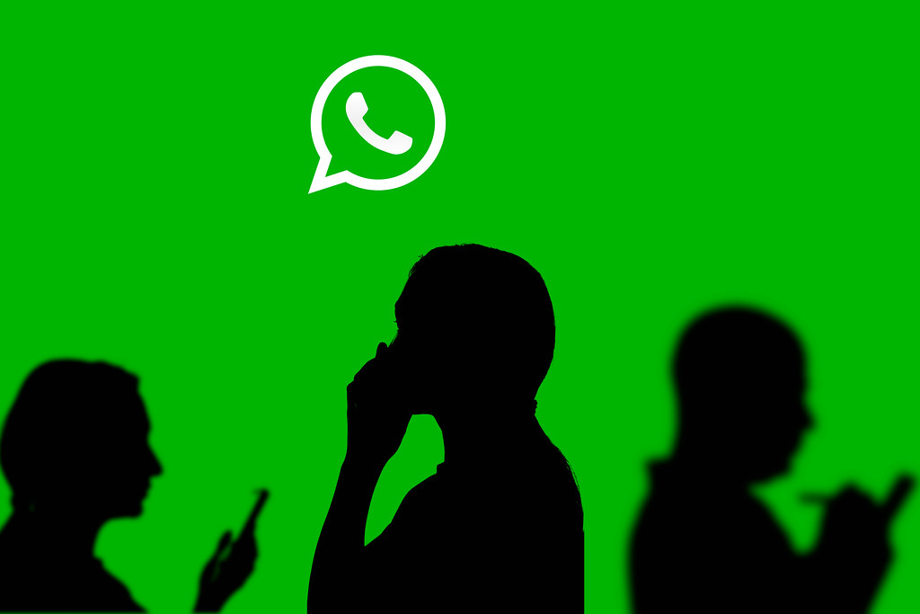 Business people shadows and whatsapp messenger logotype on a large screen