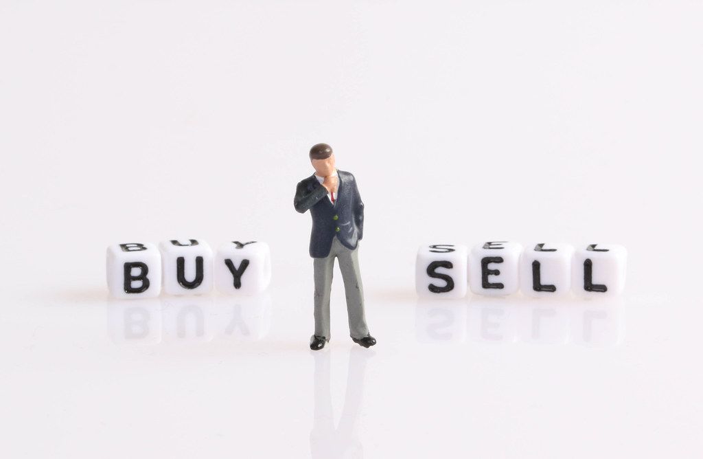 Businessman figure standing in front of Buy and Sell text