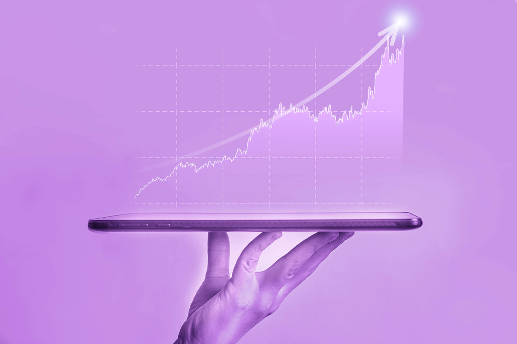 Businessman holds a tablet with holographic graphs showing stock market statistics