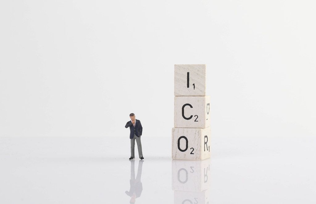 Businessman standing next to ICO text on wooden blocks