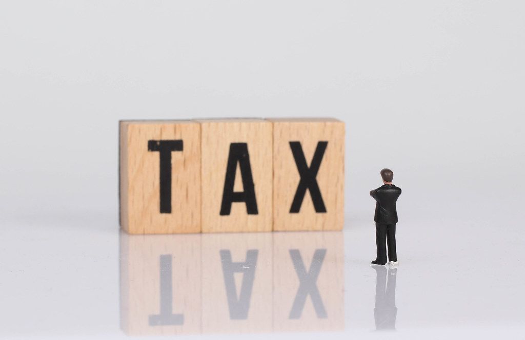 Businessman standing next to Tax text