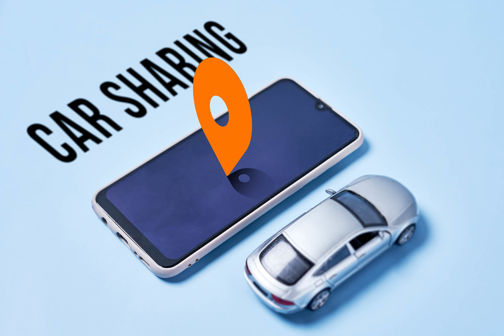 Car sharing with miniature automobile model and smartphone with location sign