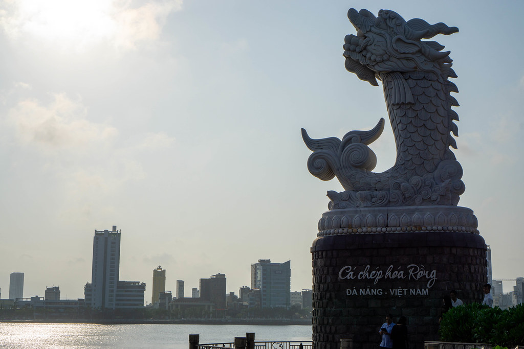 Carp Dragon Stone Statue with Sunset reflecting in Han River and Buildings in the Background  in Da Nang, Vietnam