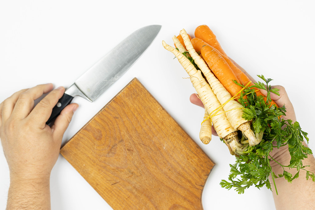 Carrot and Parsnip in the hand on the table with knife