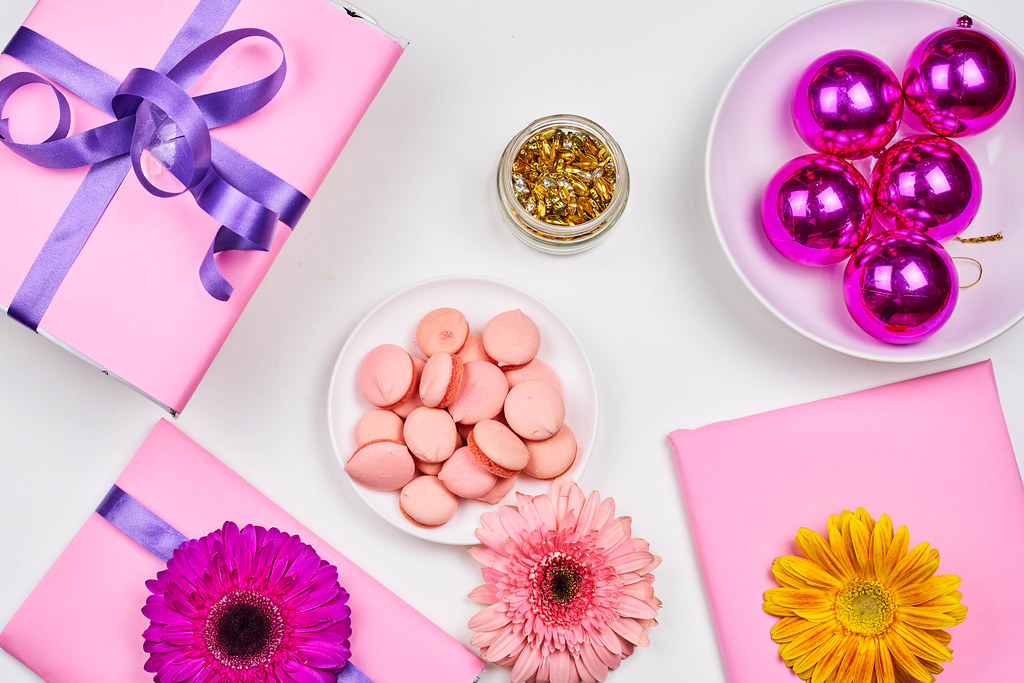 Celebrate in pink and purple: wrapped gifts, flowers, golden decoration, Christmas bulbs, macarons