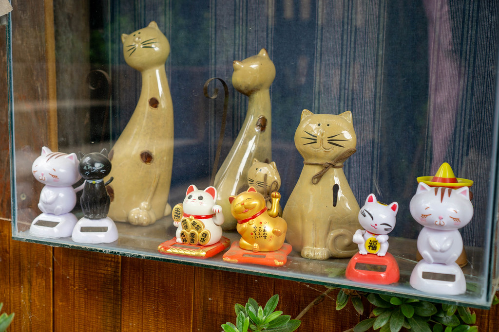 Ceramic Animal Decoration Cats and Waving Lucky Cats in different Designs in a Glass Shelf at Still Cafe in Dalat, Vietnam