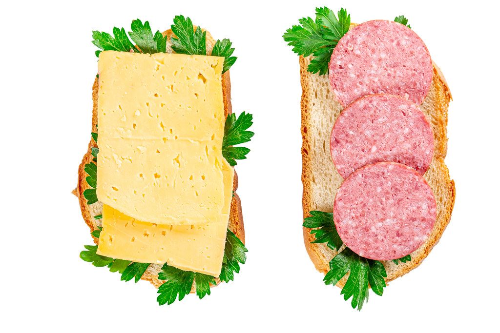Cheese and smoked sausage sandwiches with fresh parsley leaves, top view