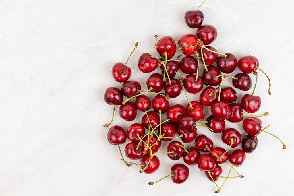 Cherries pile on the grey kitchen table with copy space