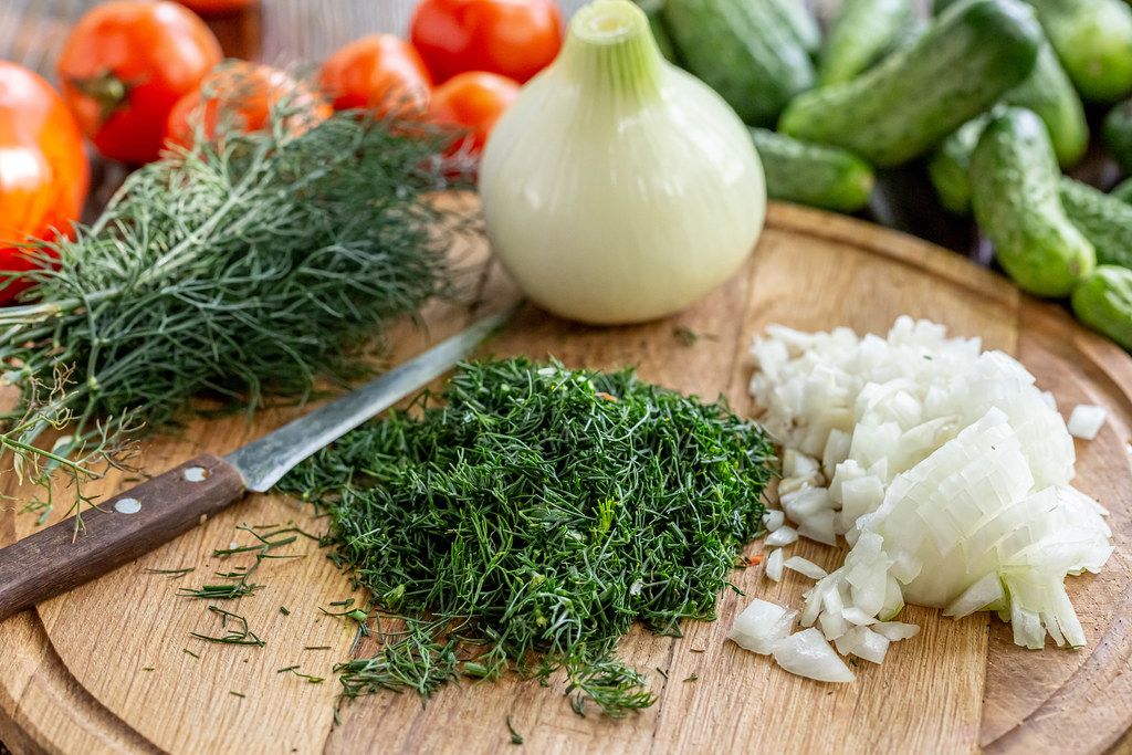 Chopped onion and dill on the kitchen board with a knife