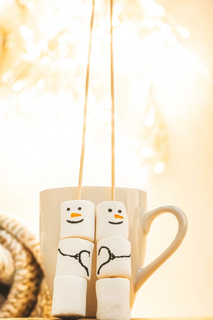 Christmas background with delicious marshmallow snowmen on bokeh background