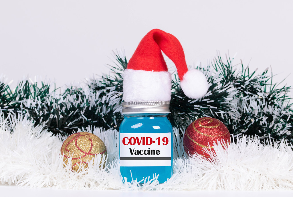 Christmas ornaments and Covid-19 vaccine bottle with Christmas hat