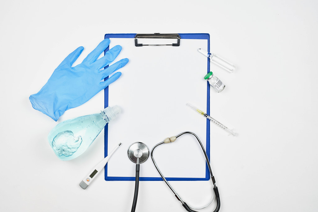 Clipboard with copy space, stethoscope, syringe, thermometer, glove, disinfectant and ampoules