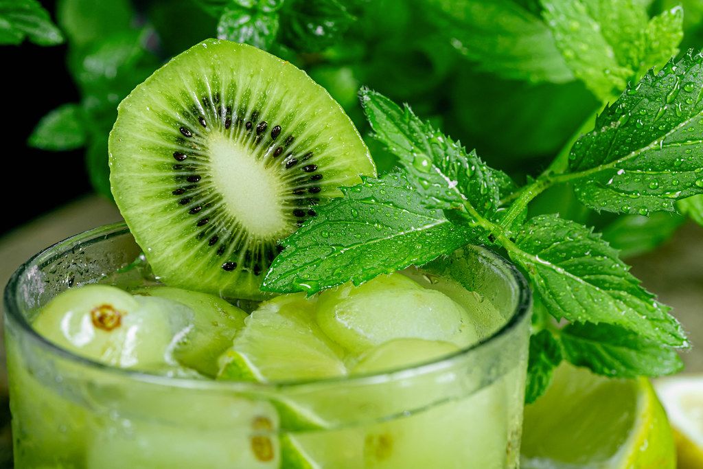 Close-up, a glass of cocktail with green fruit and fresh mint