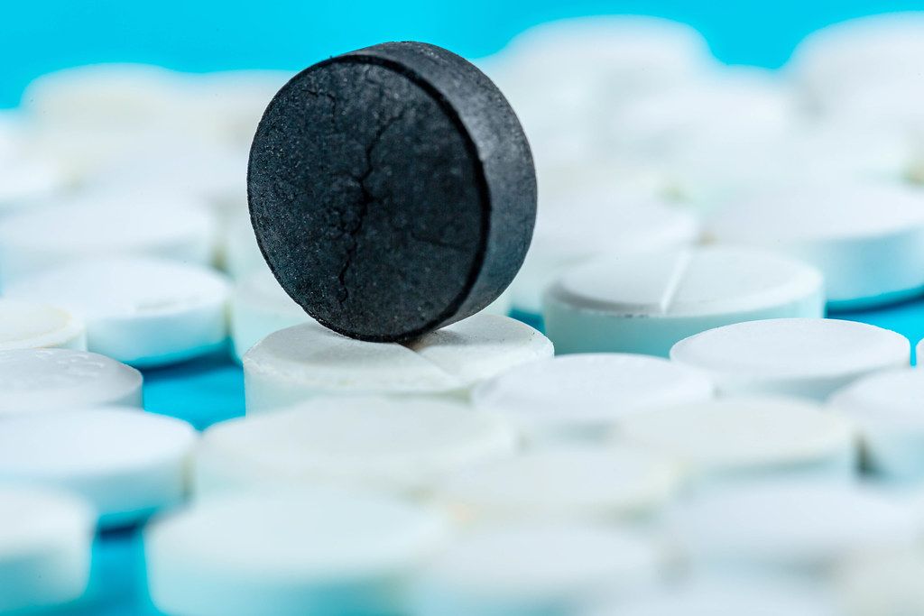 Close-up, black pill on blue background with white pills