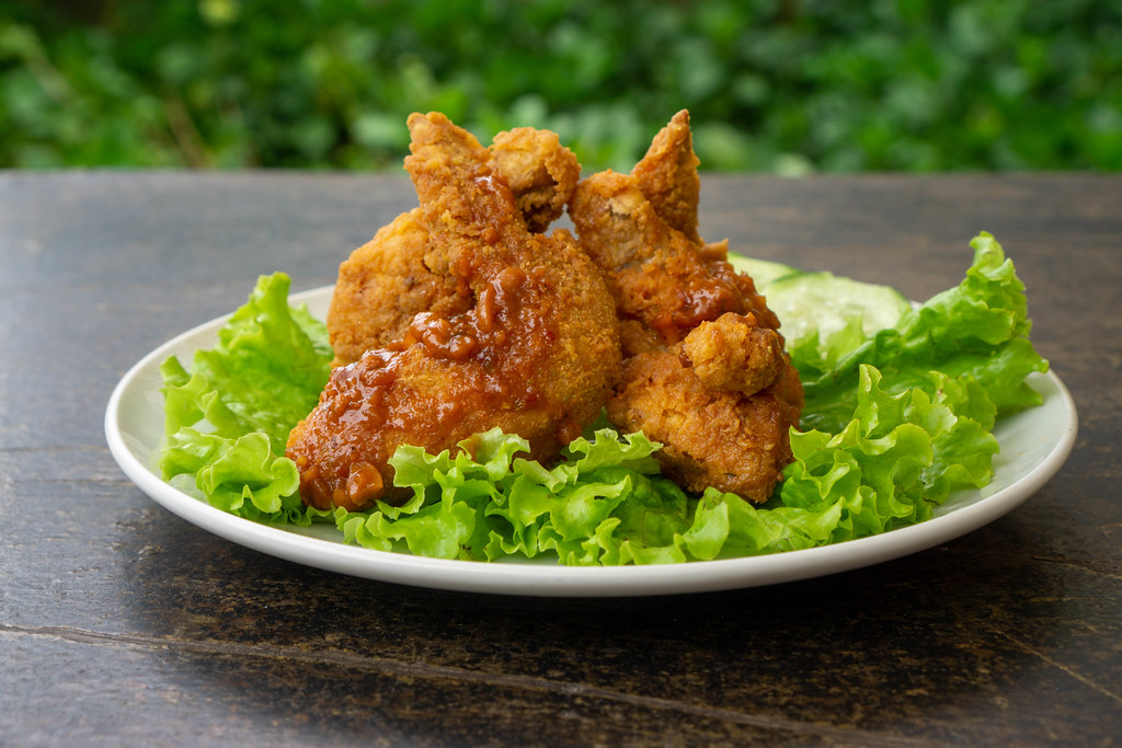 Close Up Food Photo of Fried Chicken Wings with Spicy Tomato Sauce and Lettuce on a White Ceramic Plate