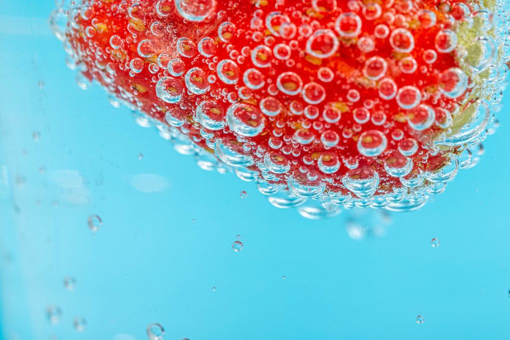 Close up, fresh red strawberries with bubbles on blue