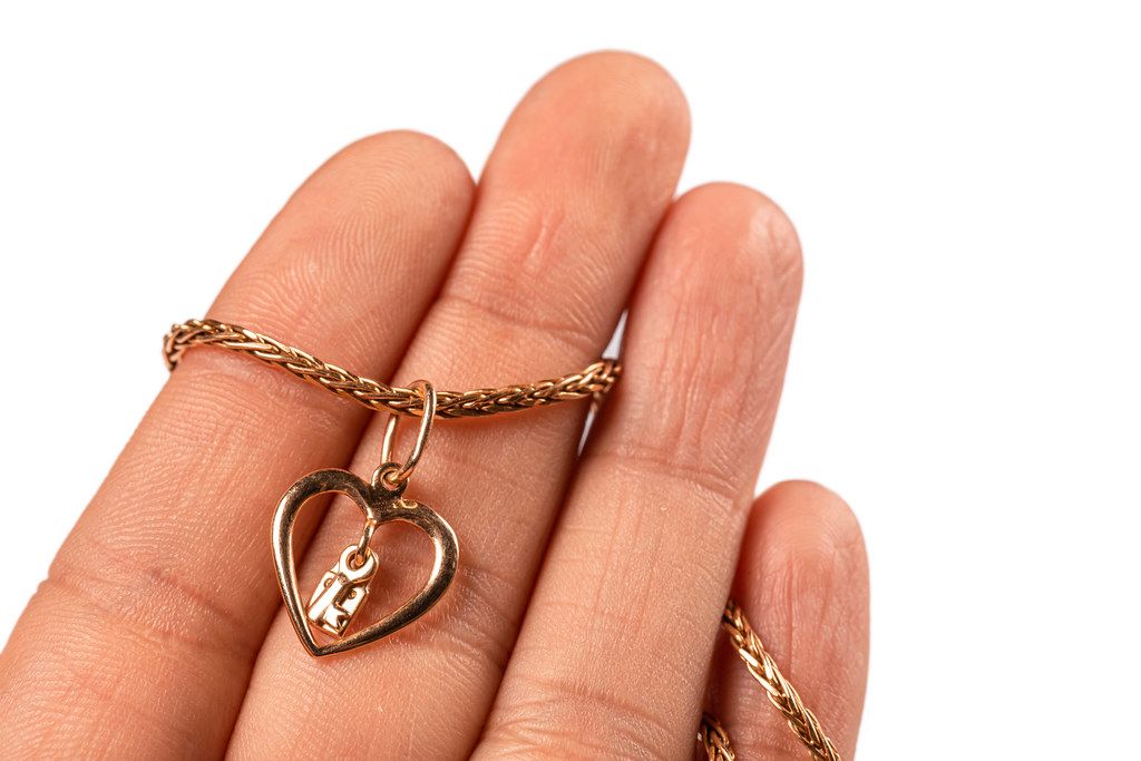Close-up, gold pendant heart with a chain in a female hand