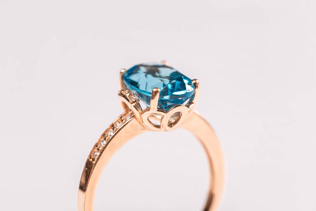 Close-up, golden ring with blue topaz on white