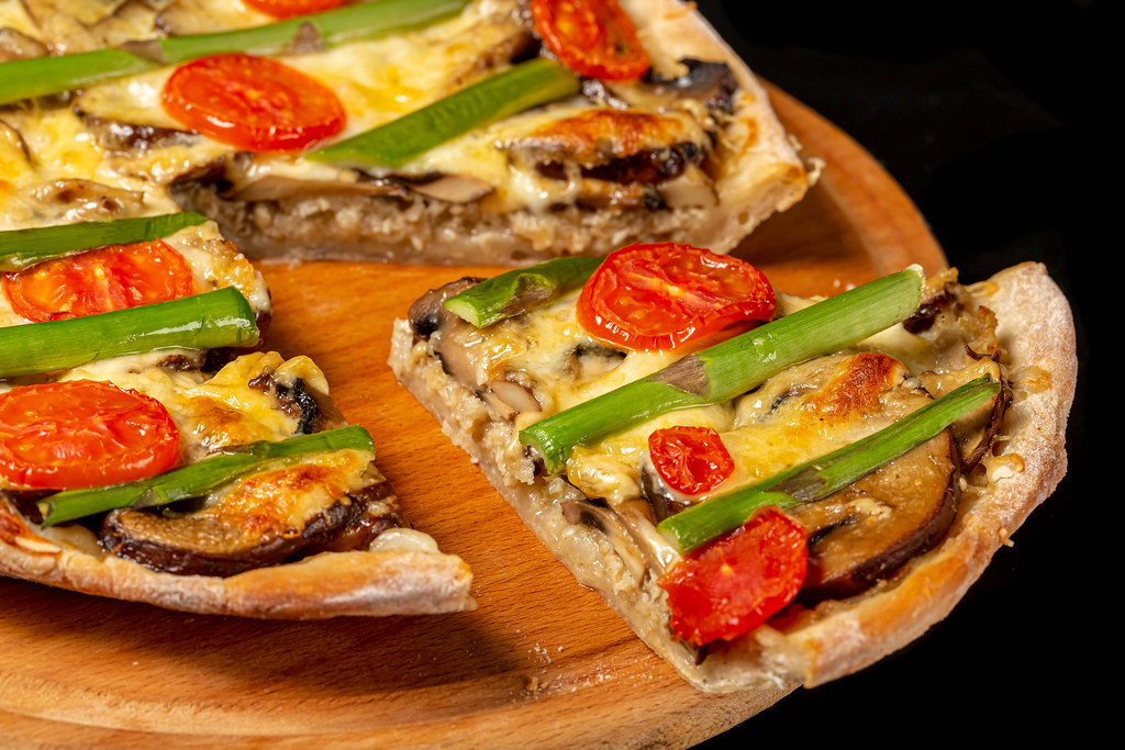Close-up, hot slice of pie with mushrooms, meat, cheese, tomatoes and asparagus