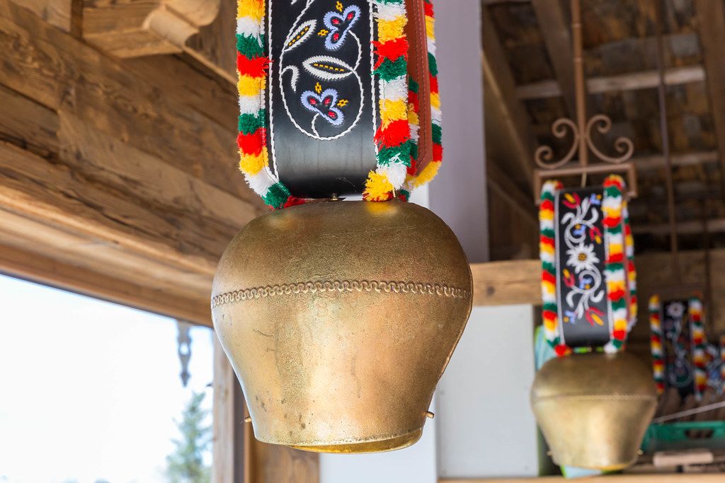 Close-up of a cow bell with colourful ribbon hanging from the ceiling: typical Alpine decoration in Austria