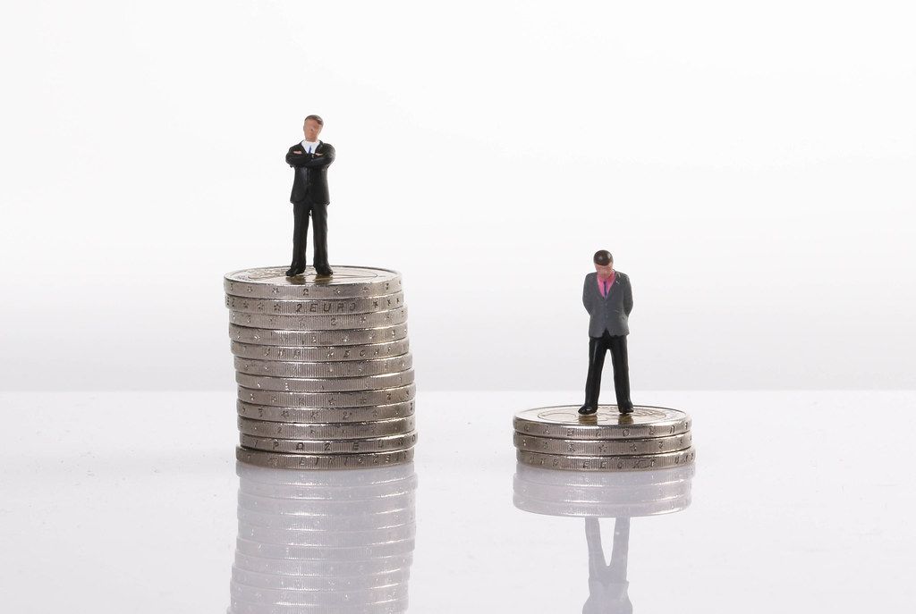 Close up of businessman miniature people figures standing with stack of coins