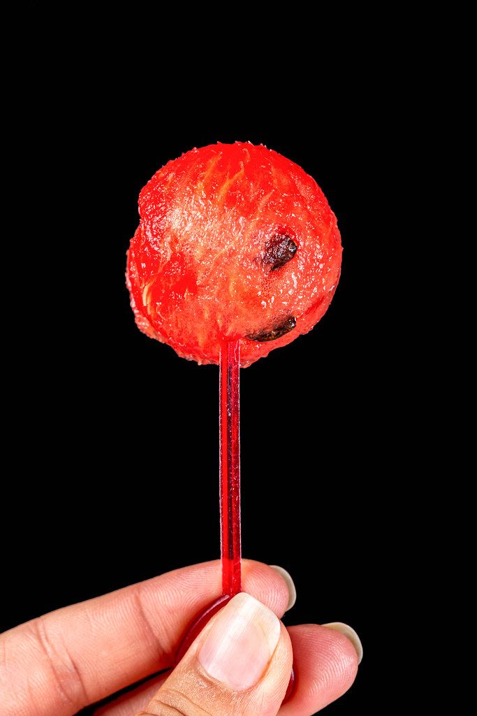Close-up of fresh red watermelon ball in women hand on black