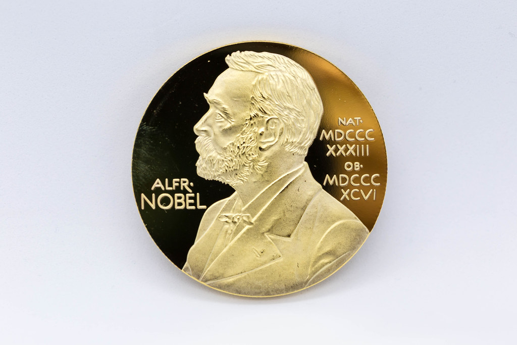 Close-up of gold medal with portrait of Alfred Nobel against white background