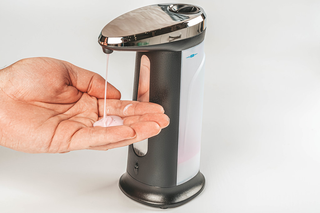 Close up of male hand uses automatic soap dispenser