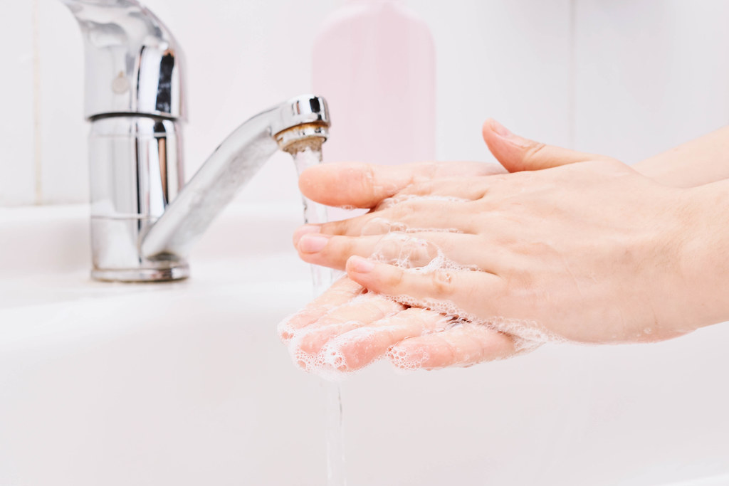 Close-up of woman hands washing hands with soap under the faucet with water