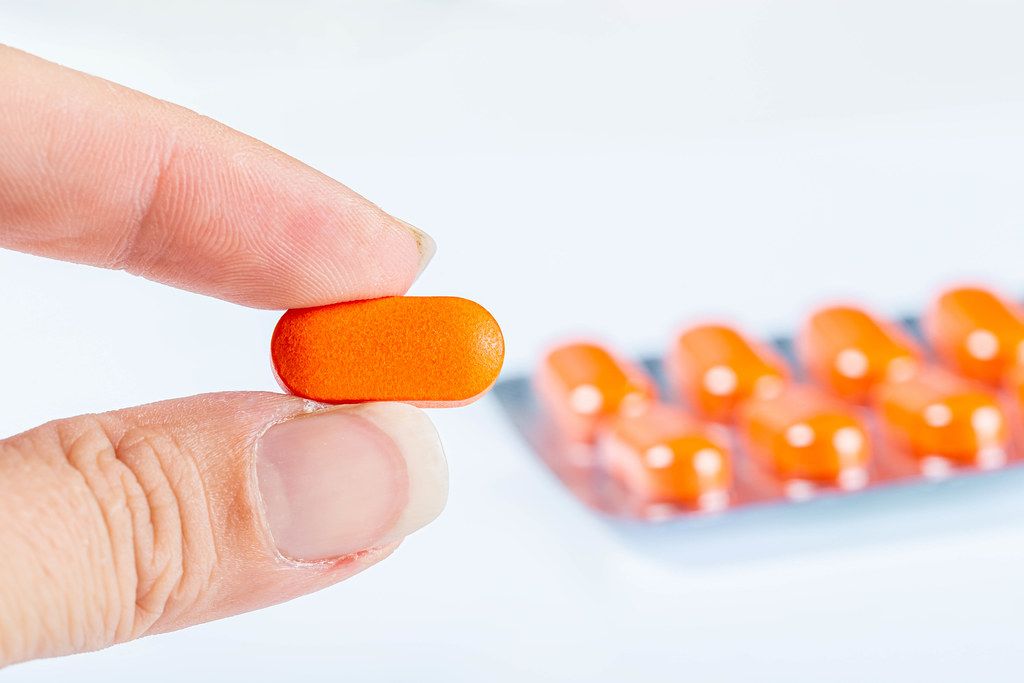 Close-up, orange pill in a woman