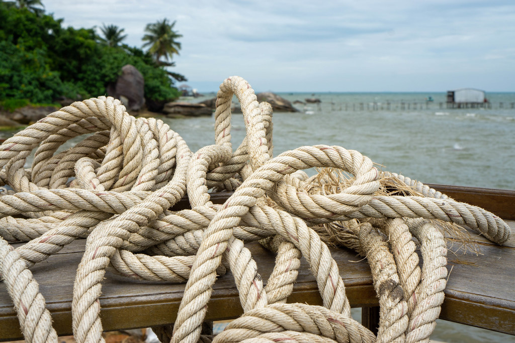 Close Up Photo of Nautical Ropes on a Wooden Bar Table with Ocean and Tropical Forest in the Background